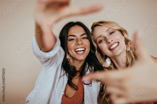 Blithesome blonde girl spending free time with best friend. Wonderful european sisters funny posing in studio.
