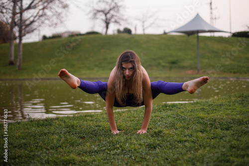 Yoga model stretching her body during a workout session at the park. Shot with natural light at sunset.