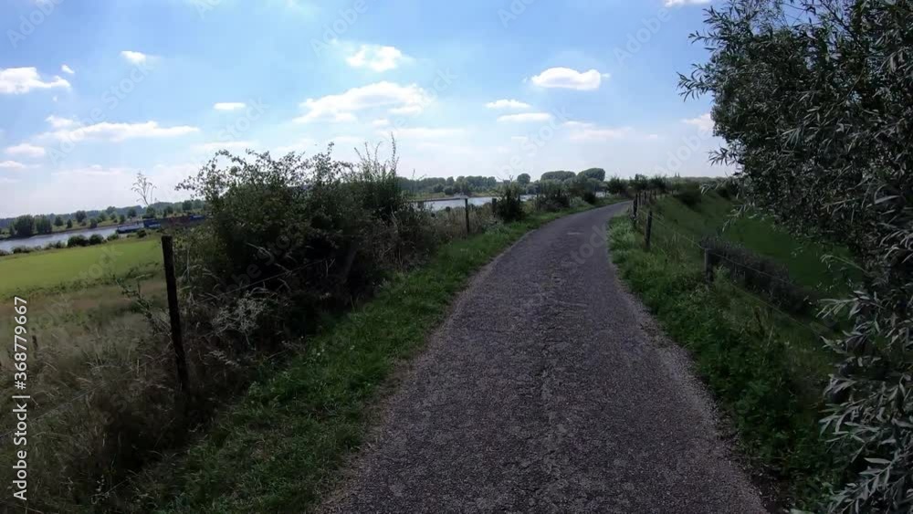 Radfahren aus der Sicht des Fahrers entlang einer alten Deichstraße - Schiffe auf dem Rhein Radfahren aus der Sicht des Fahrers entlang einer alten Deichstraße - Schiffe auf dem Rhein