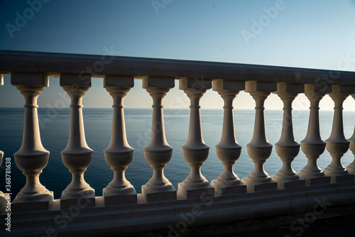 Classic balustrade on the embankment against the sea. White balcony over the sea. Promenade with a beautiful view of the sea on a clear day. Close-up of the balustrade by the sea