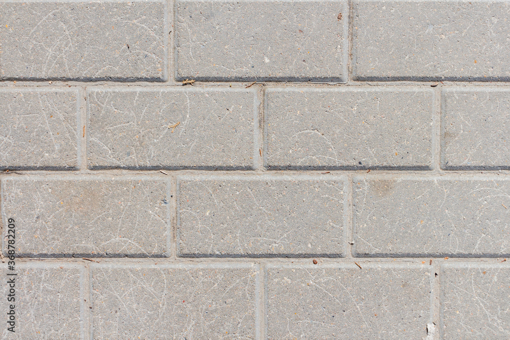Gray stone tiles lies on the sidewalk. There are scratches on the stones in some places. Abstract textured background. Copy space for your text and decorations. Gray stone tiles lies on the sidewalk. There are scratches on the stones in some places. Abstract textured background. Copy space for your text and decorations.