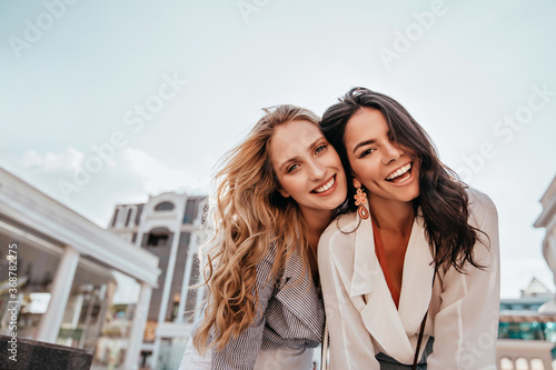 Ecstatic long-haired girls posing in spring day on sky background. Outdoor photo of two good-looking female friends. photo