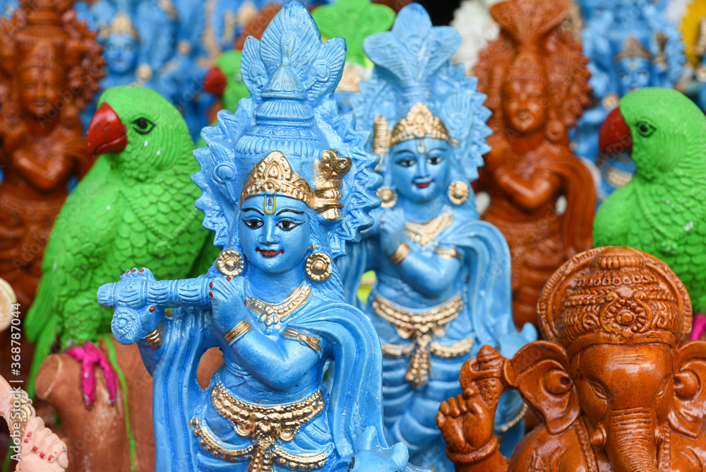 Indian handicraft statue of god Lord Krishna, many handmade colorful sculptures of Hindu god displayed street shop, Delhi, India. birth celebrated as Janmashtami. 