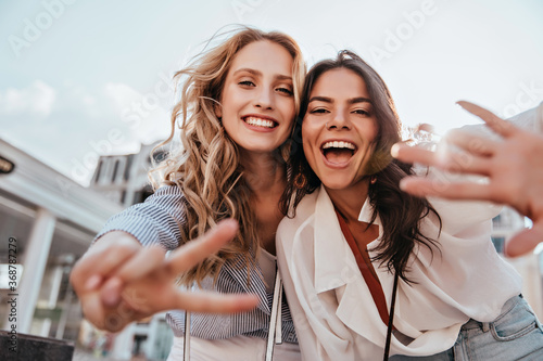 Lovable caucasian girls expressing positive emotions to camera. Outdoor photo of refined sisters posing on sky background. photo