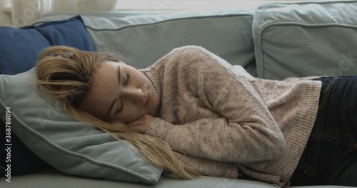 Young sleepy woman falling down on sofa at home.
