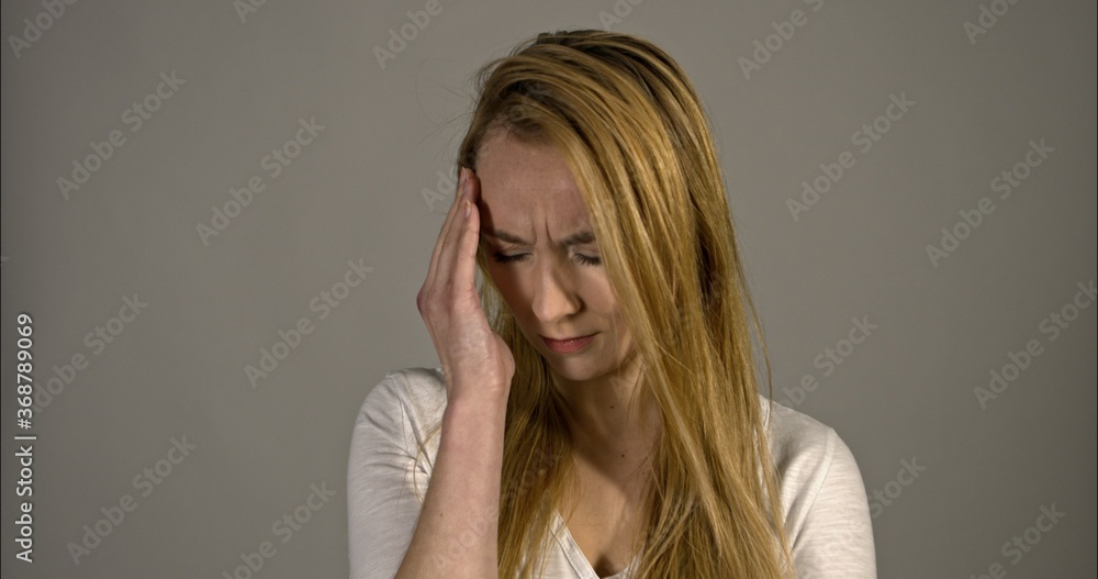 A young woman with a headache holding head.