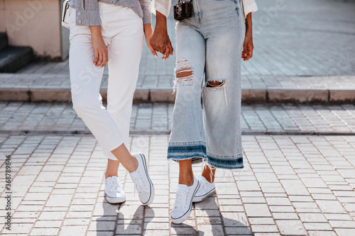 Obraz na plátne Glamorous girl in white gumshoes standing with legs crossed
