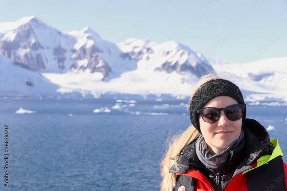 Blond woman on expedition ship with sunglasses, before glaciers, Antarctica