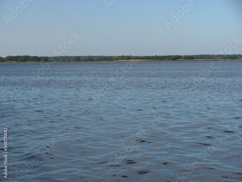 large water area with ripples and forest on the horizon