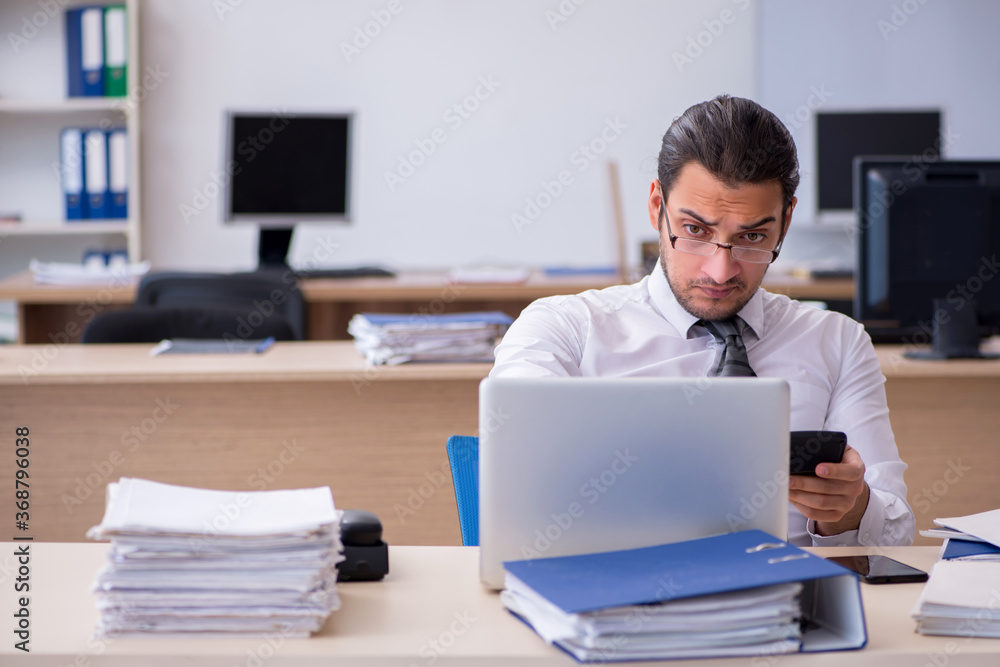 Young male employee unhappy with excessive work Young male employee unhappy with excessive work