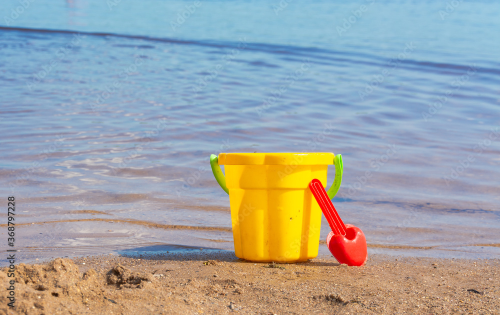 Children's toy bucket with a scoop on the sandy beach. Children's toy bucket with a scoop on the sandy beach.
