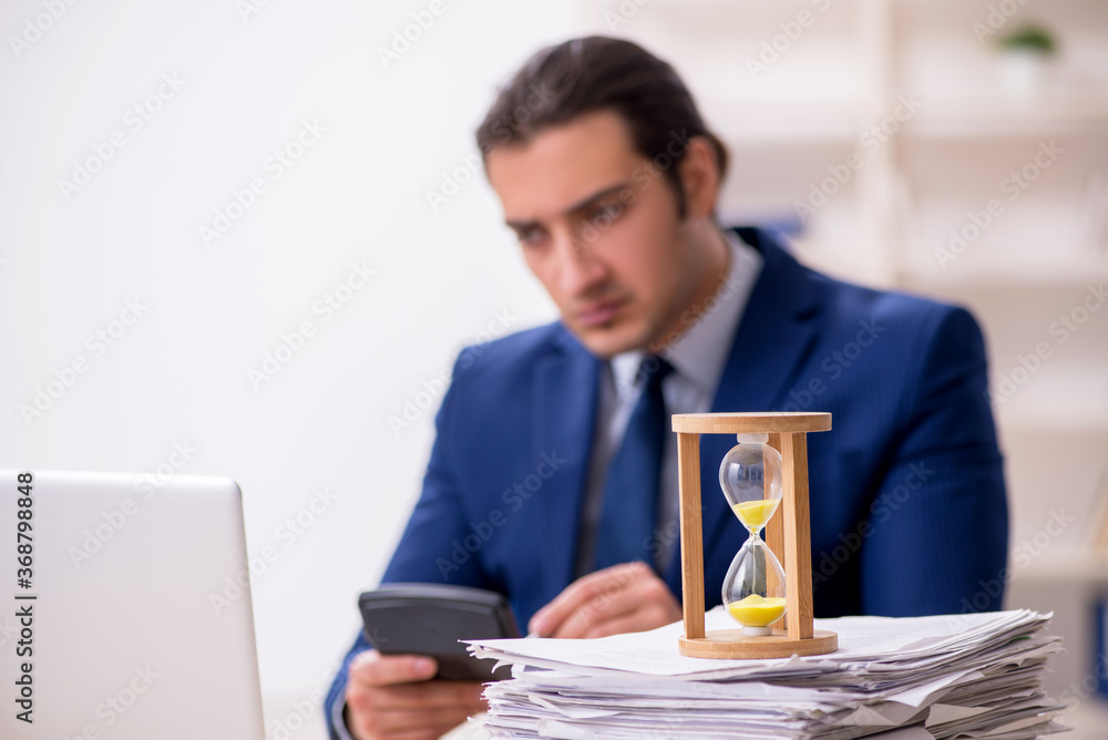 Young male employee in time management concept Young male employee in time management concept