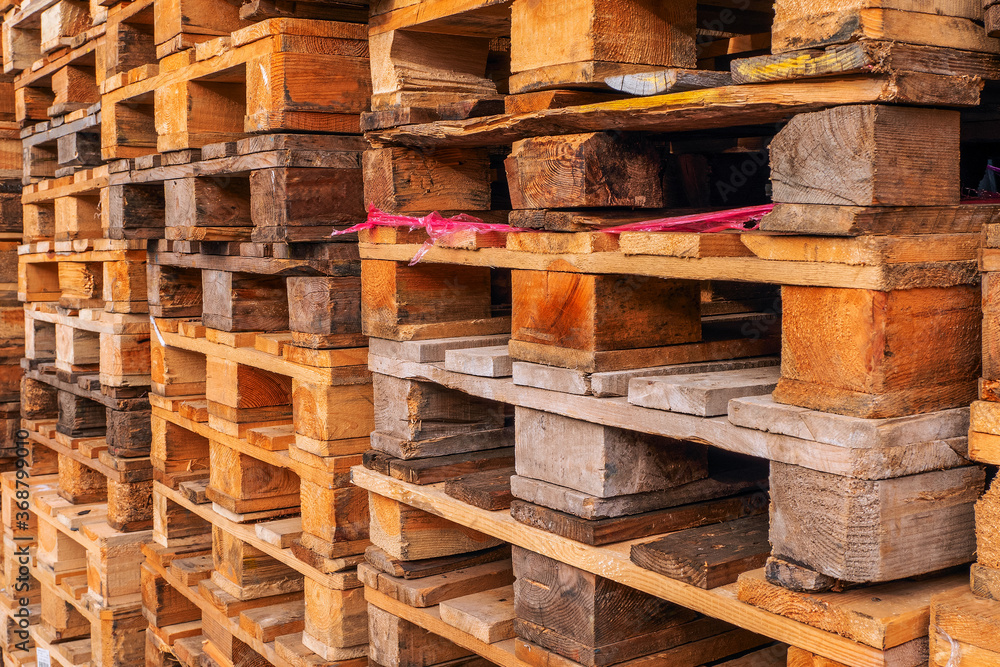 A lot stacks of used wooden pallets of euro type on warehouse is ready for recycling. Industrial background. Close-up. A lot stacks of used wooden pallets of euro type on warehouse is ready for recycling. Industrial background. Close-up.