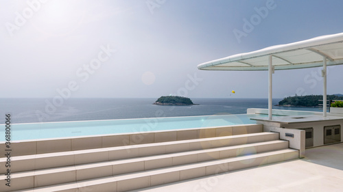 Swimming pool overlooking view andaman sea and clear sky background and lens flare copy space for summer holiday background concept.