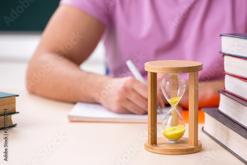 Young male student in the classroom at time management concept