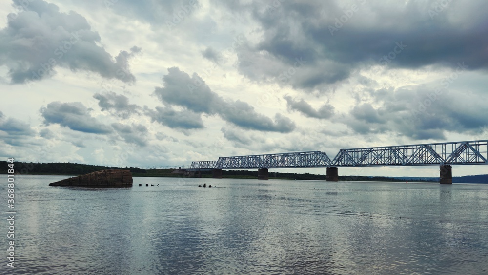 railway bridge over the river against the backdrop of a gloomy cloudy sky