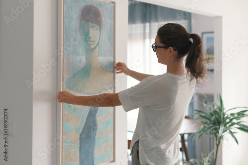 Εκτύπωση καμβά Woman hanging a painting at home