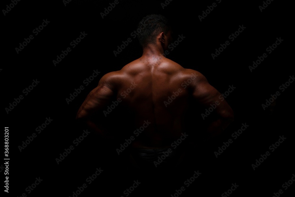 Silhouette of young athlete bodybuilder man on black