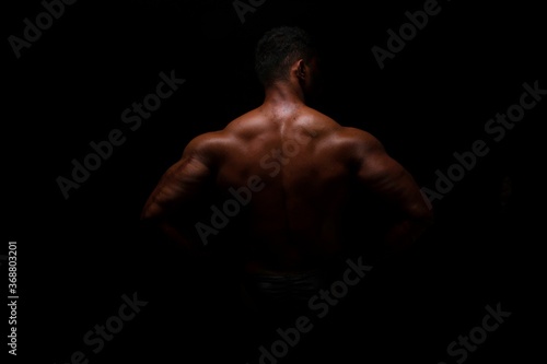 Silhouette of young athlete bodybuilder man on black