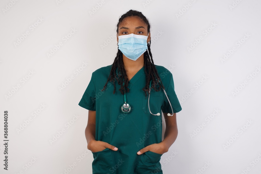 Confidence and business concept. Portrait of charming successful young doctor woman, smiling broadly with self-assured expression while holding hands in pockets. Confidence and business concept. Portrait of charming successful young doctor woman, smiling broadly with self-assured expression while holding hands in pockets.