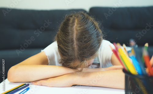 Young schoolgirl tired of drawing at home.