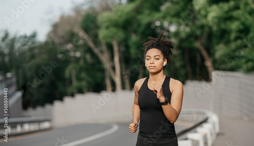 Fit and healthy woman. Concentrated african american girl running on walkway