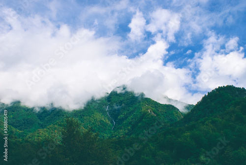 Landscape misty panorama. Fantastic dreamy sunrise. Foggy clouds above forrest. Smoky mountain landscape with mountain and light 