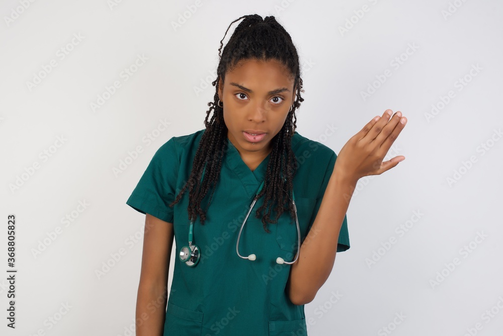 What the hell are you talking about, nonsense. Studio shot of frustrated doctor female gesturing with raised palm, frowning, being displeased and confused with dumb question over gray wall. What the hell are you talking about, nonsense. Studio shot of frustrated doctor female gesturing with raised palm, frowning, being displeased and confused with dumb question over gray wall.