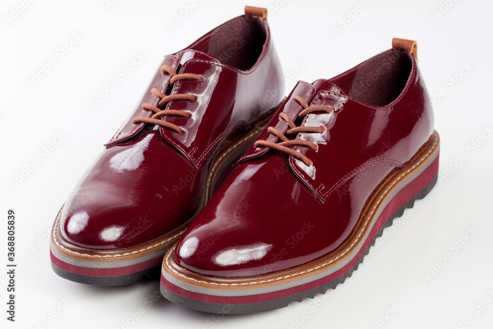 Deep red shiny pair of shoes on a white background.