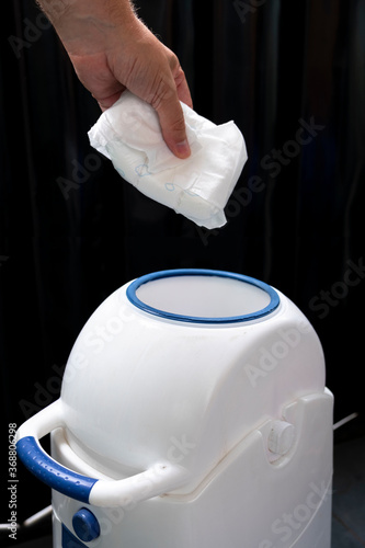 We throw the baby diaper into the waste bin. Rubbish in the trash can.