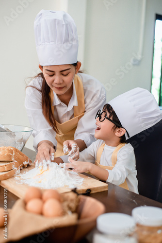 Mom teaching son for cooking food. Mother and kid daily lifestyle at home. Asian family together in the kitchen. photo