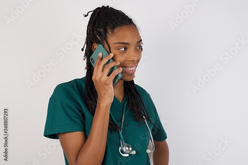 Lifestyle Concept - Portrait of beautiful Caucasian joyful woman talking on mobile phone with friend. Yellow pastel studio background. Copy Space.