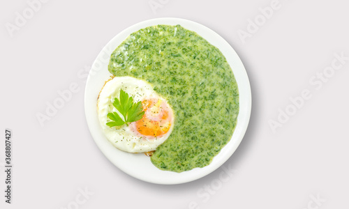 Fried egg with spinach sauce on a white background