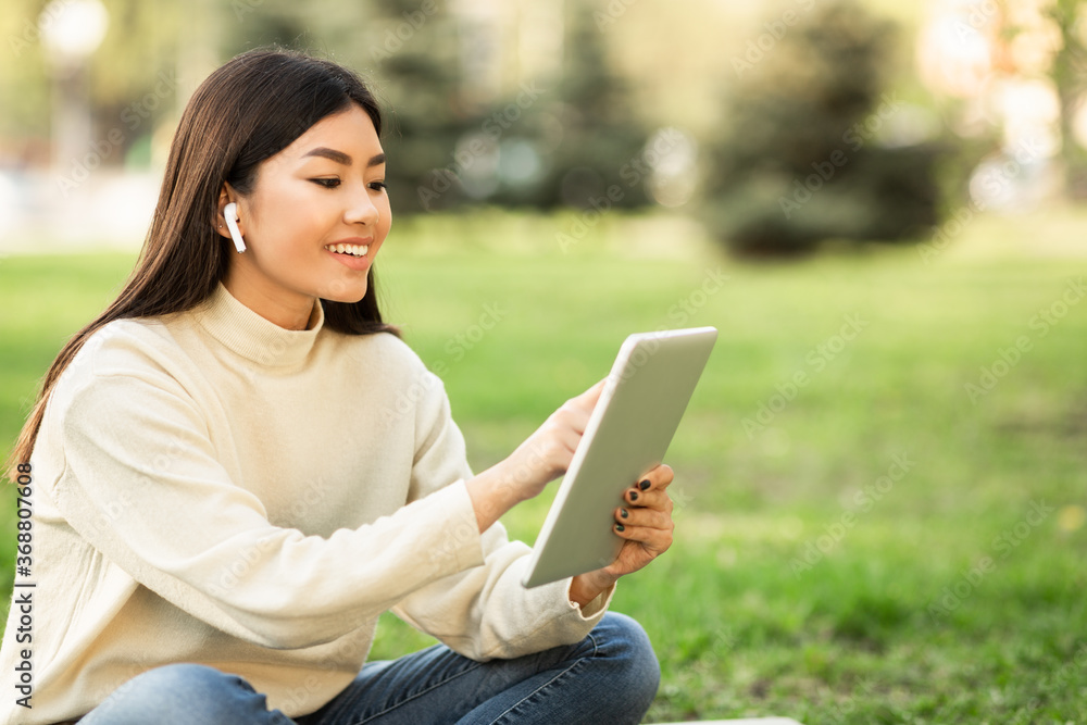 Female student using tablet, sitting in the park Female student using tablet, sitting in the park