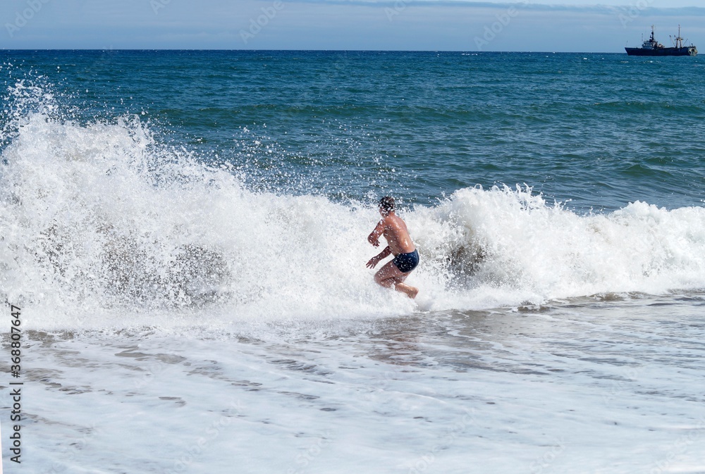 child swims on large sea waves with splashes child swims on large sea waves with splashes