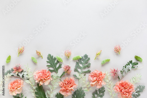 White and coral flowers and silver-green leaves on pastel grey background. Flowers composition with copy space, flat lay.