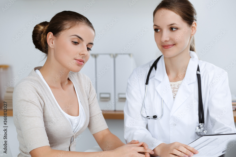 Doctor and patient are sitting and discussing health examination results in clinic office. Health care, medicine and good news concepts Doctor and patient are sitting and discussing health examination results in clinic office. Health care, medicine and good news concepts