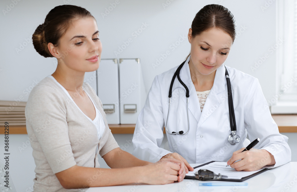 Doctor and patient are sitting and discussing health examination results in clinic office. Health care, medicine and good news concepts Doctor and patient are sitting and discussing health examination results in clinic office. Health care, medicine and good news concepts