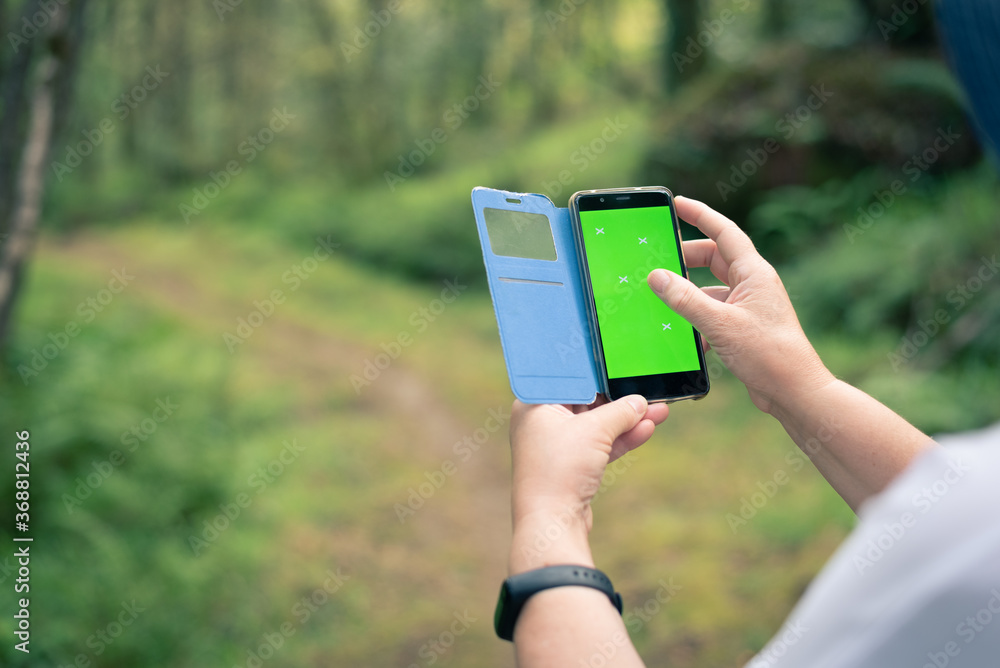 Senior lady hands using smartphone in the forest