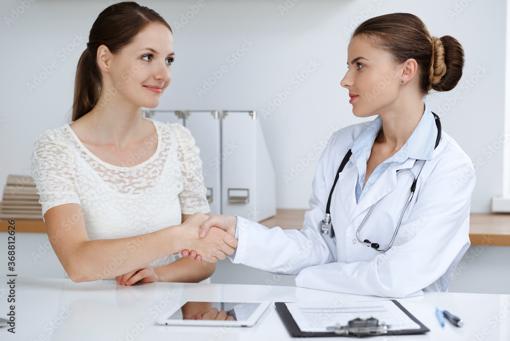 Woman-doctor reassuring her female patient while sitting at the desk. Medicine concept Woman-doctor reassuring her female patient while sitting at the desk. Medicine concept