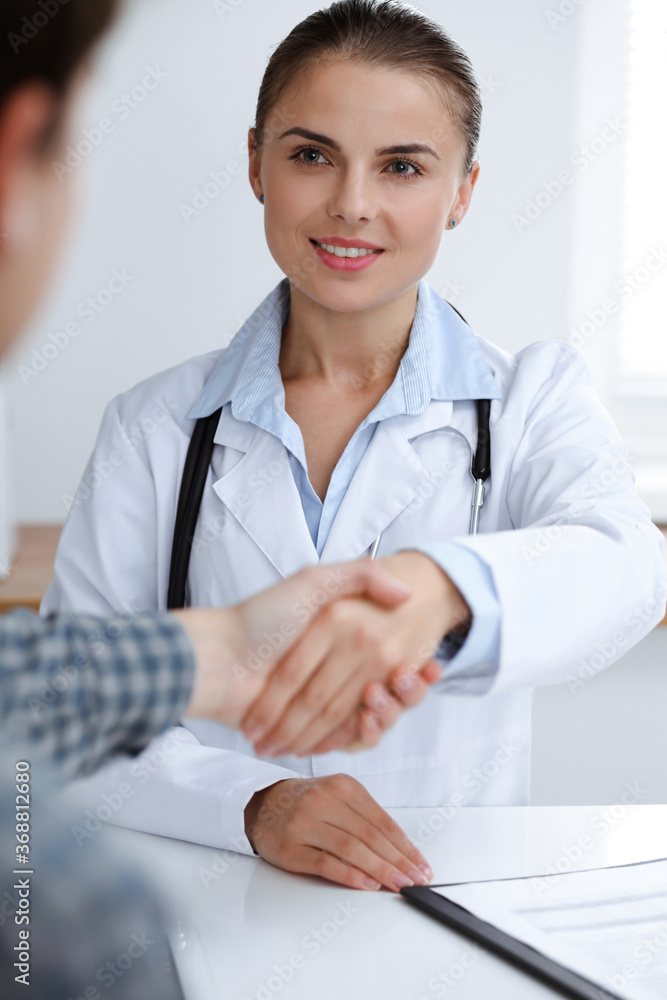 Woman-doctor smiling while shaking hands with her male patient. Medicine concept Woman-doctor smiling while shaking hands with her male patient. Medicine concept