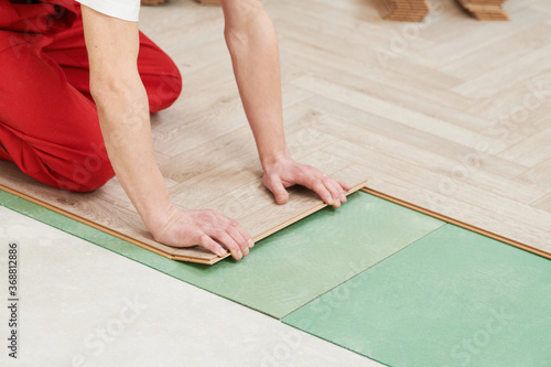 worker laying laminate floor covering at home renovation © Kadmy