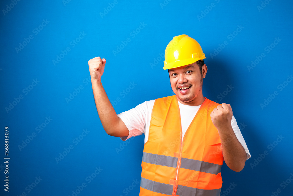 Asian man worker wearing safety helmet looking happy celebrating his victory Asian man worker wearing safety helmet looking happy celebrating his victory