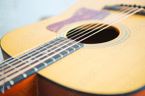 Close up of acoustic guitar with metal strings on a wooden table.