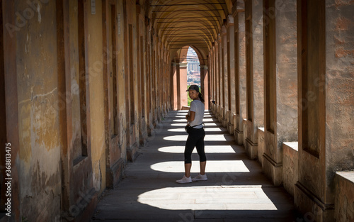 Woman in hat standing in portico with shadows and looking back © David