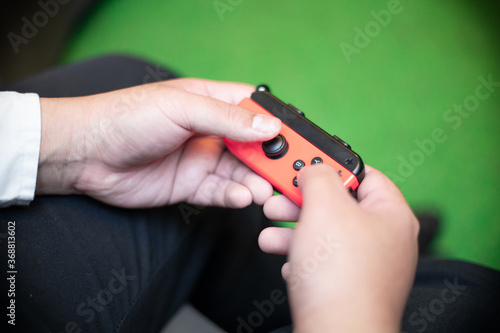 Closed up of guy's hands playing on the red game console. a wireless console controller. Enjoying free time concept. Preoccupied with video game.
