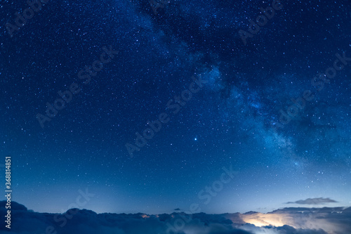 Starry blue sky above a sea of clouds at night. Night photography of long exposure landscapes with the Milky Way and the immensity of the universe.