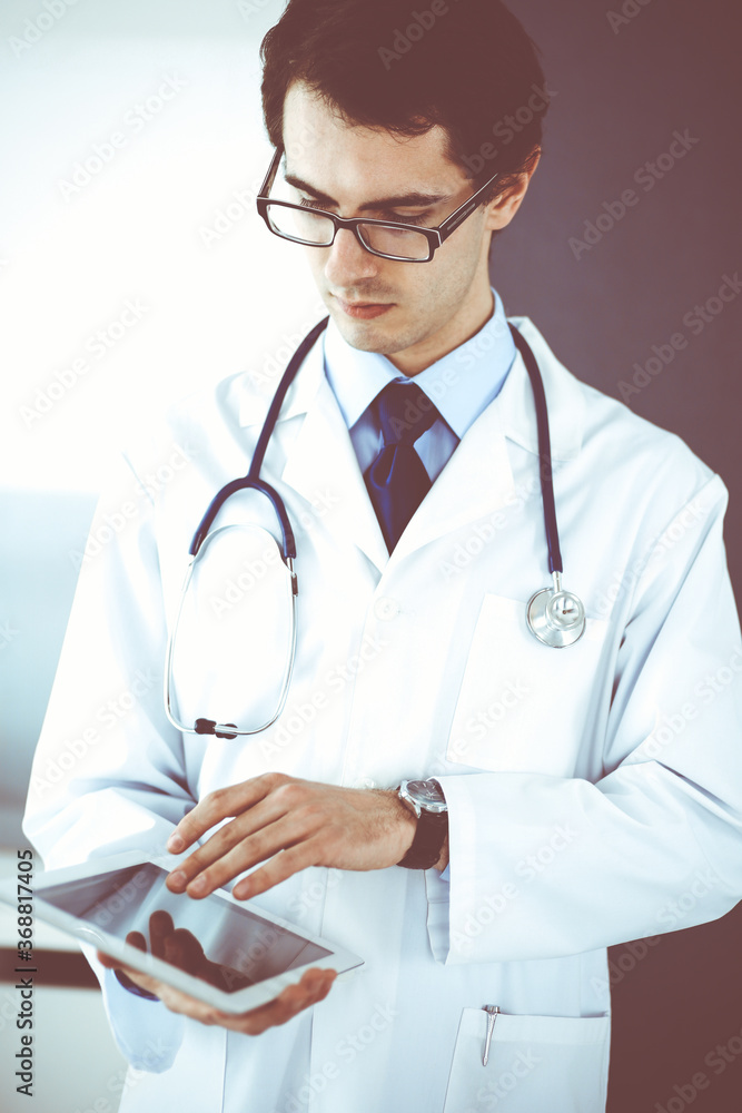 Doctor man using tablet computer for network research or virtual disease treatment. Perfect medical service in clinic. Modern medicine, medic data and healthcare concepts
