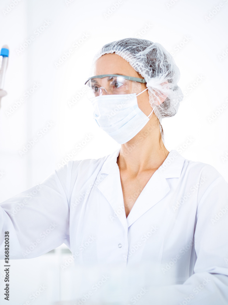 Professional female scientist in protective eyeglasses researching tube with reagents in laboratory. Concepts of medicine and science researching Professional female scientist in protective eyeglasses researching tube with reagents in laboratory. Concepts of medicine and science researching