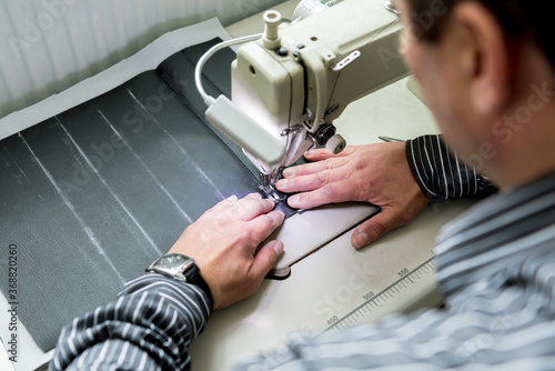 Designer tailor sew seat covers. Man use sewing machine for his work.